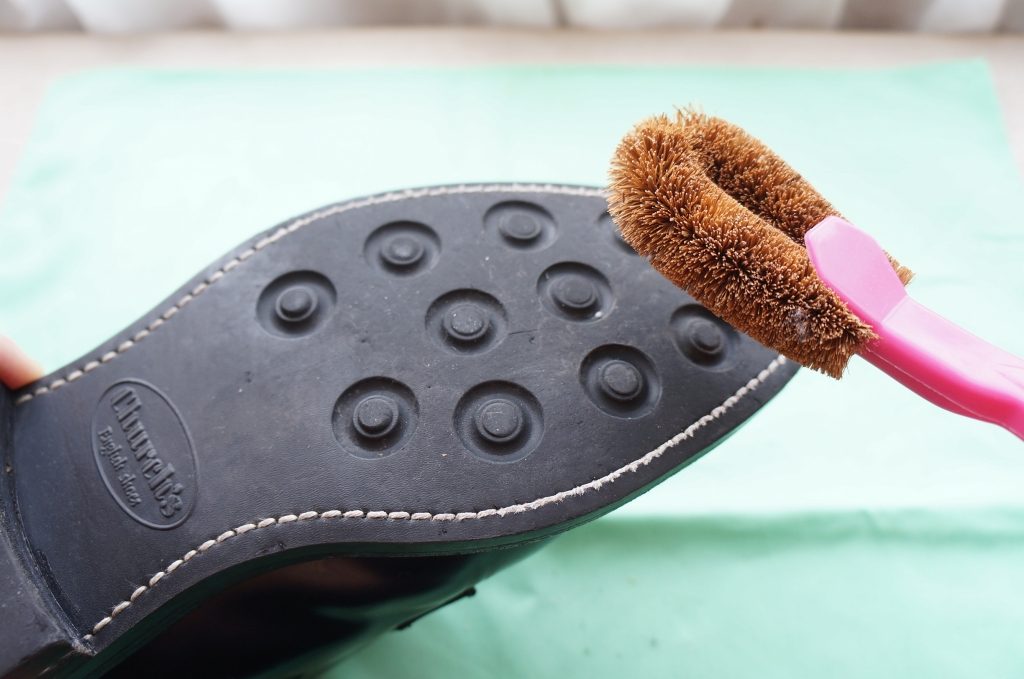 靴底をタワシで清掃する